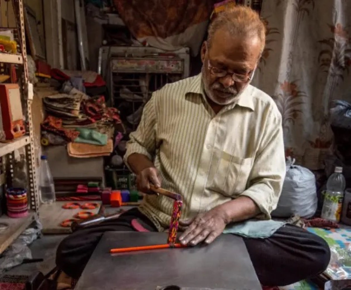 An artisan decorating a bangle by hand with a traditional tool
